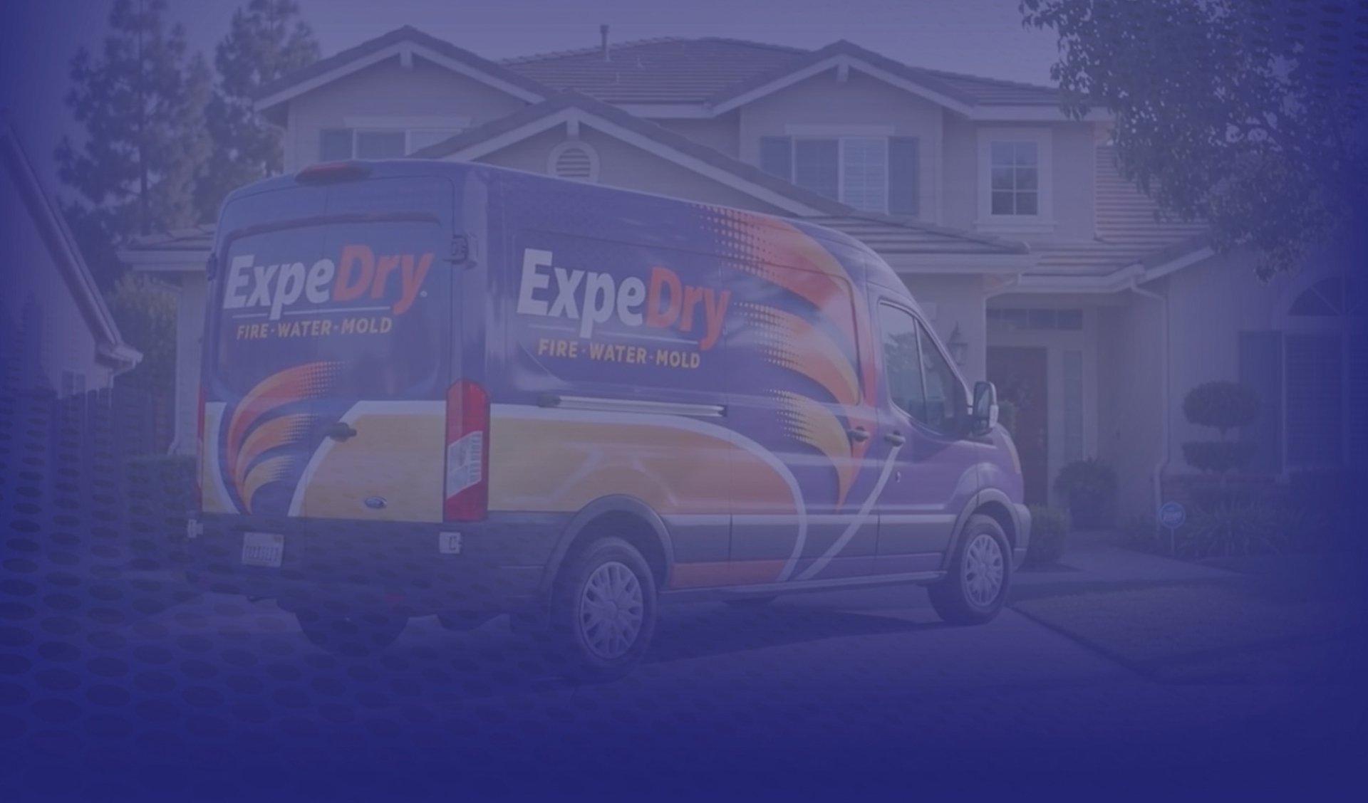 A restoration company service van parked in the driveway of a two-story suburban home.